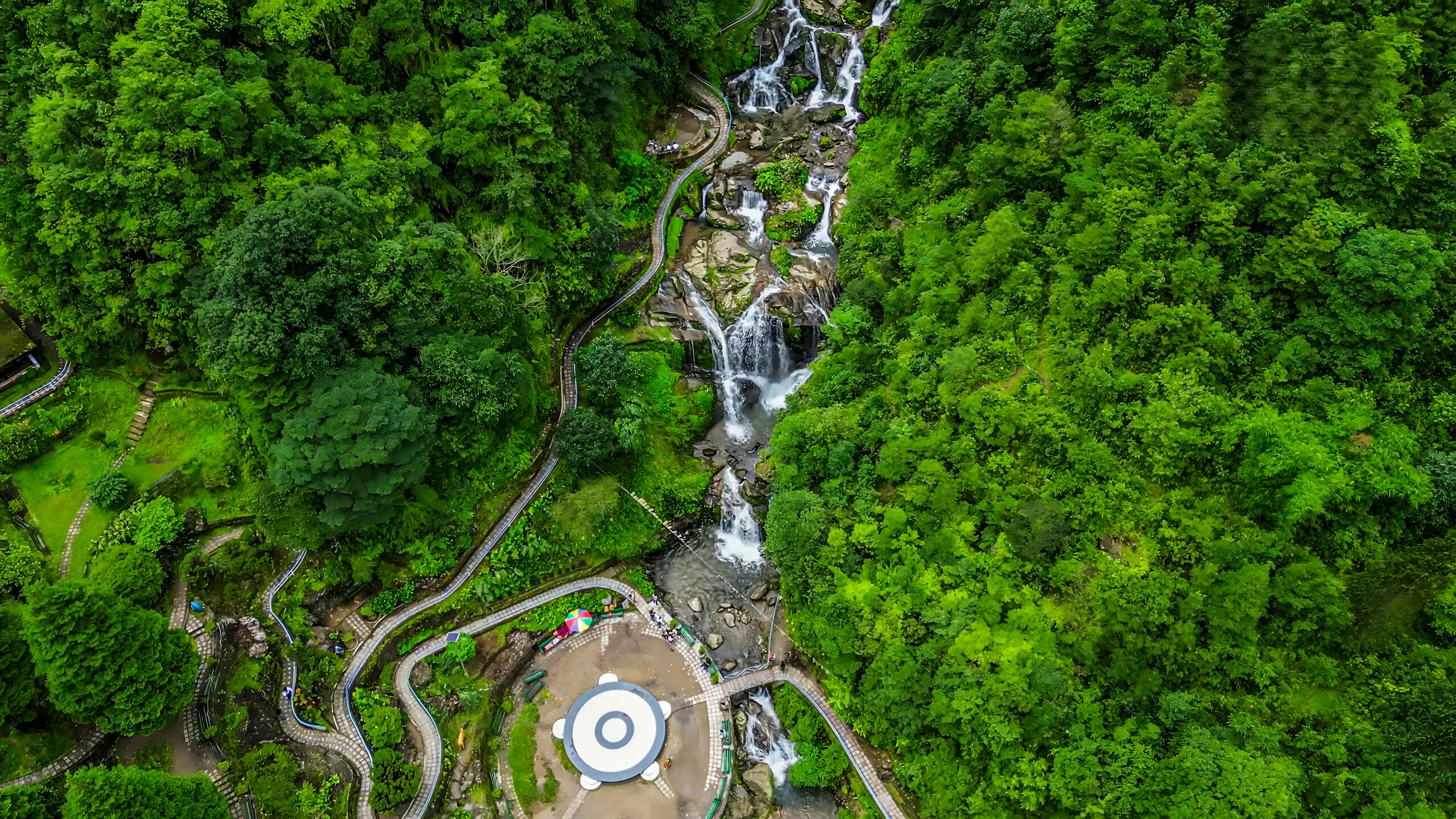 Top view of waterfall, forest greenery, and walking paths in Darjeeling hills.
