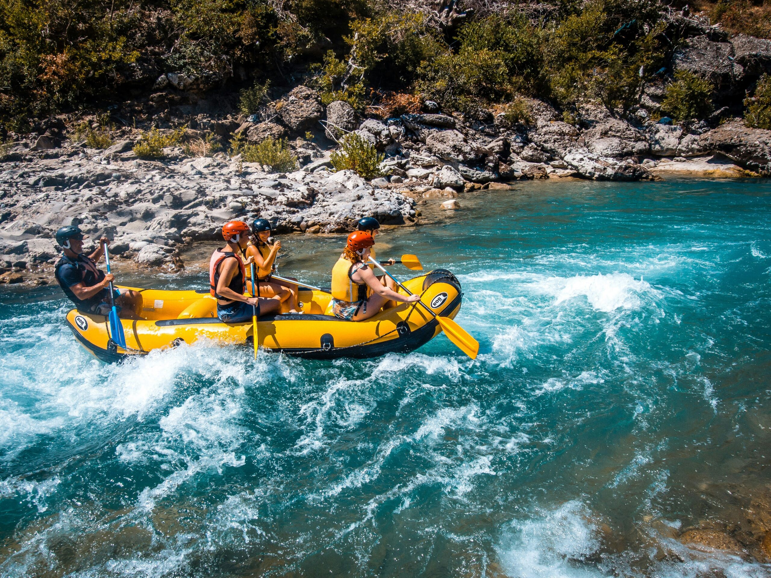 Group of tourists enjoying river rafting in Darjeeling on turquoise rapids.