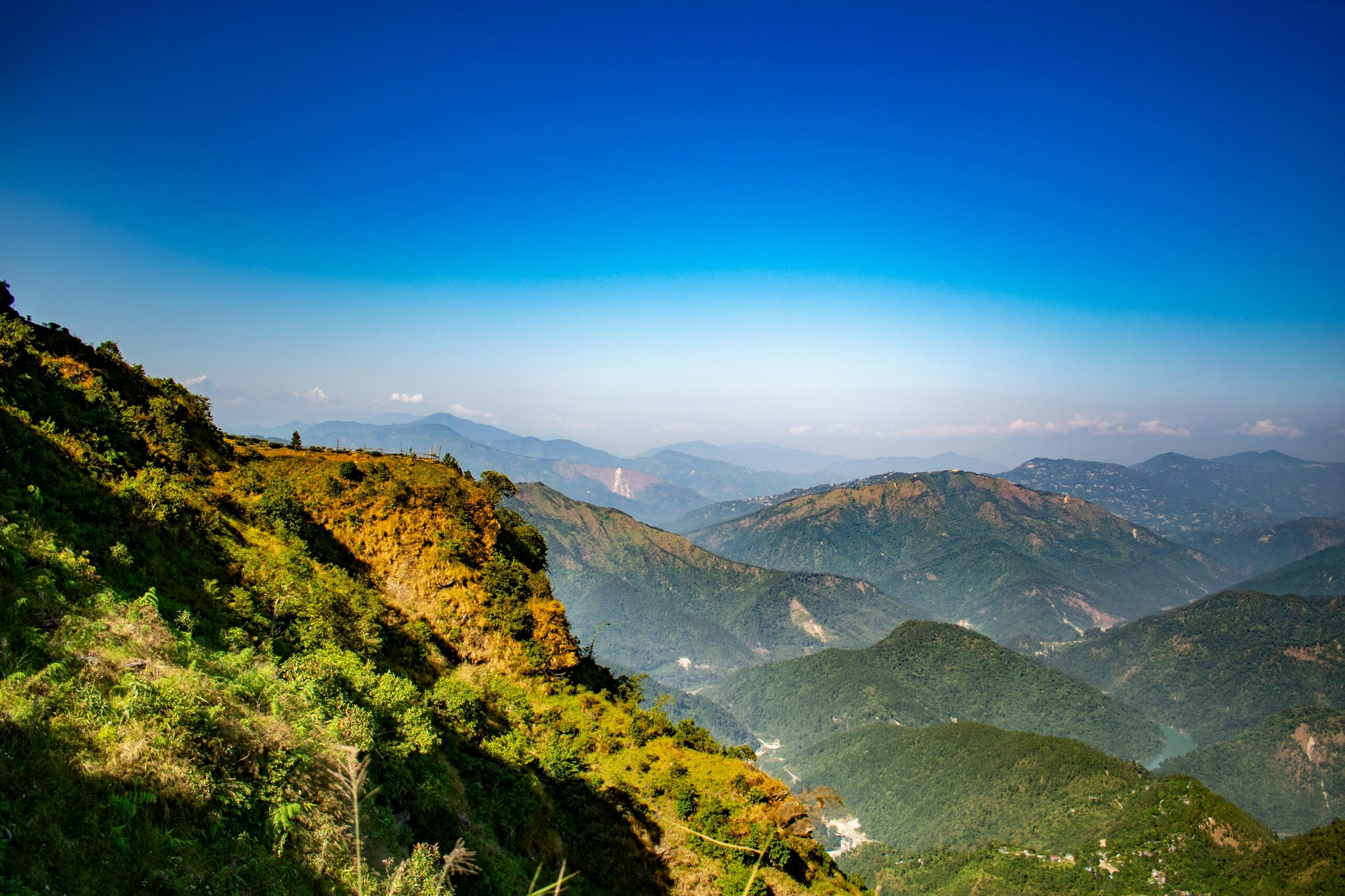 Scenic green hills and layered Himalayan ranges under a clear sky in Darjeeling.